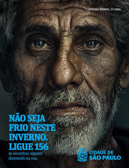  A imagem mostra a foto do rosto de um morador em situação de rua, com a escrita embaixo em azul "Não Seja Frio Neste Inverno, ligue 156 se encontrar alguém dormindo na rua". No rodapé está o logotipo da Cidade de São Paulo.